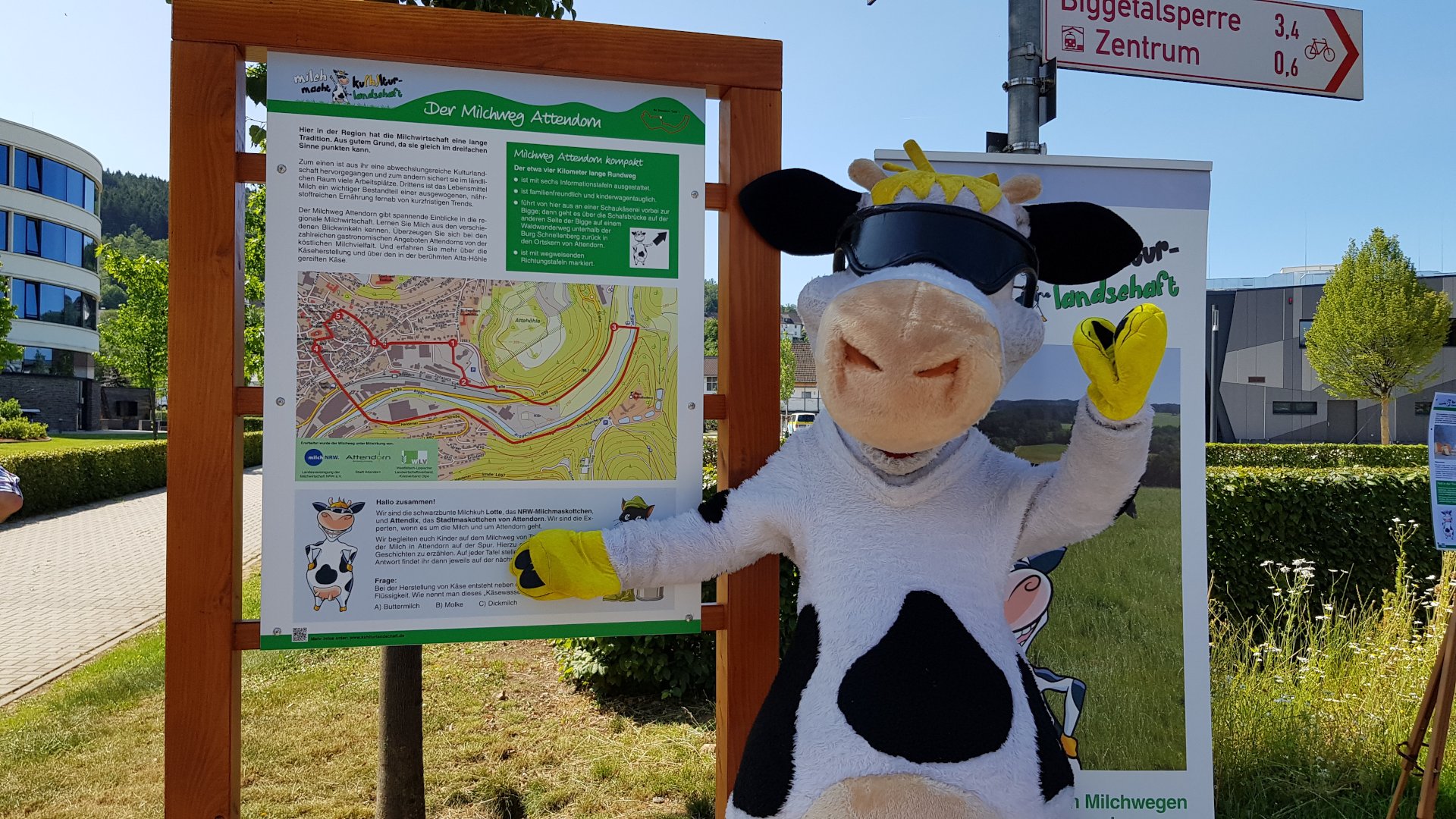 Foto: Milch-Maskottchen "Lotte" vor einer Info-Tafel der Milchwege (Copyright: milch-nrw.de)